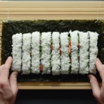 Step-by-step guide on how to fold a sushi burrito using a bamboo mat.